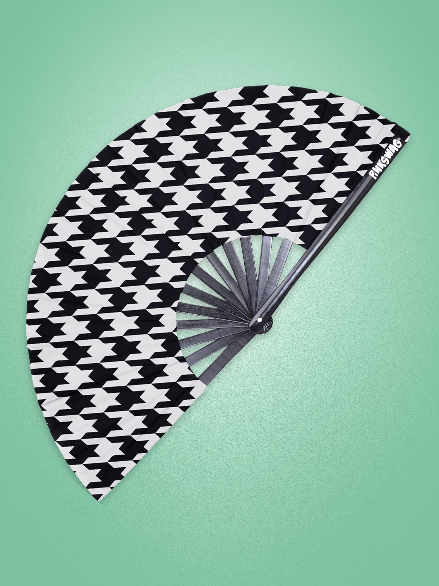 Black and white patterned hand fan on a green background