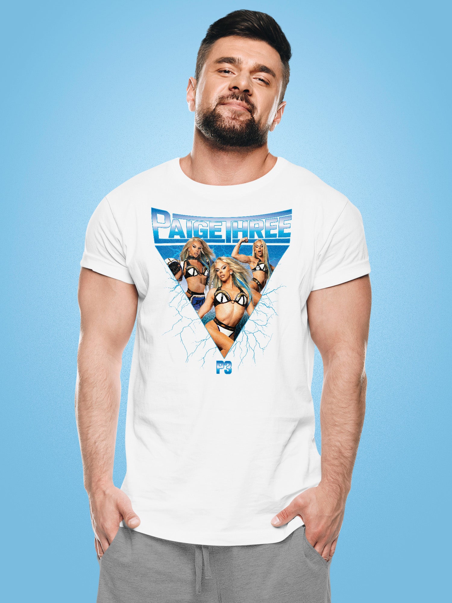 Man wearing a white t-shirt from Paige Three from BBC RuPaul's Drag Race UK Season 7 with graphic design on a blue background