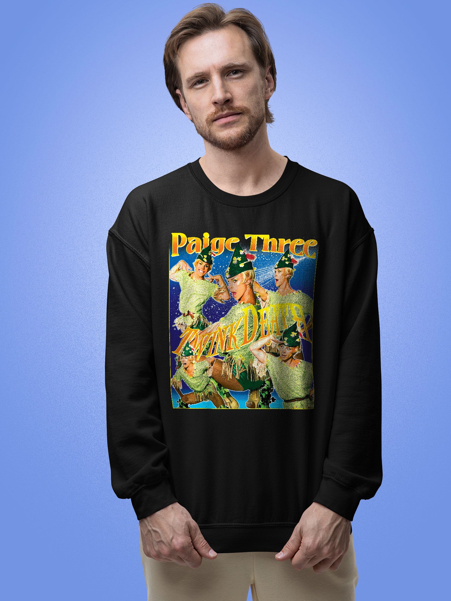 Man wearing a black sweatshirt with a colorful graphic design on a blue background. Paige Three from BBC RuPaul's Drag Race UK Season 7